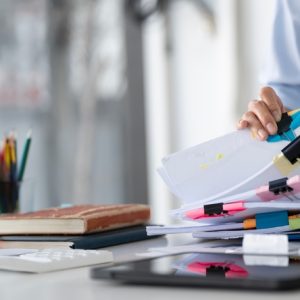 A pile of papers on a desk, used to illustrate a piece on automated compliance.