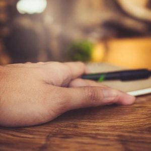 An AI-generated human hand on a desk with an errant finger, used to illustrate an op-ed about AI hallucinations.