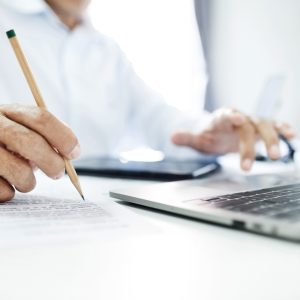 A photo of a lawyer writing on a laptop and a legal pad, used to illustrate an article about AI lawyers.
